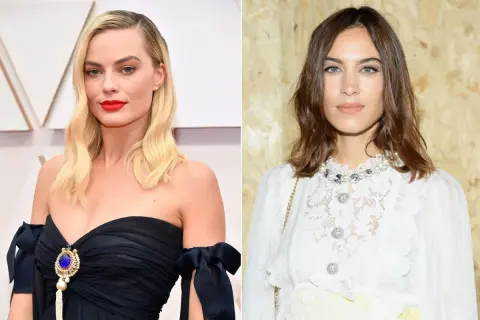 Margot Robbie z przedziałkiem z boku i rudymi ustami obok Alexy Chung w białej koronkowej bluzce.