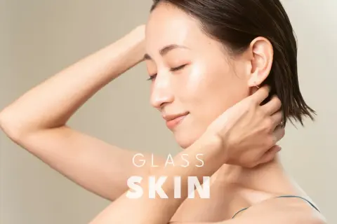 Kobieta z idealną, lśniącą cerą typu "glass skin", z dłońmi za głową.