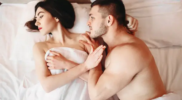 Para, co to seksapil? Mężczyzna szepcze coś kobiecie w ucho, leżąc w łóżku.